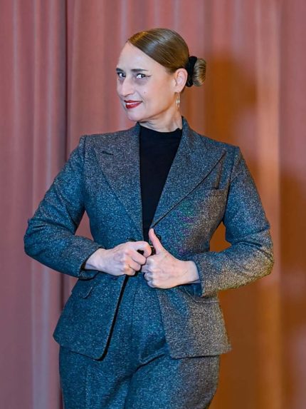 rau in einem grauen Tweed-Hosenanzug bestehend aus dem Blazer Lady Grey und einer weiten Marlene-Hose im Stil der 20er bis 30er Jahre vor einem rosa Vorhang.