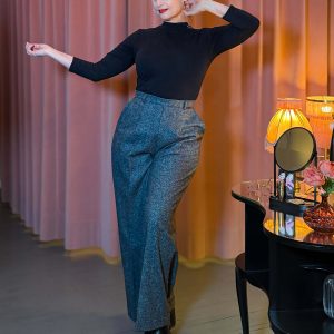 Frau trägt die taillenhohe Marlene-Hose Lady Grey aus grauem Tweed mit Bügelfalten und weitem Bein im Stil der 30er Jahre in einem Vintage-Ambiente.