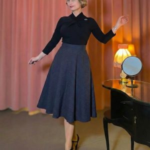 Model trägt einen klassischen Vintage Tellerrock in Schwarz mit Seitentaschen und hoher Taille, kombiniert mit einem eleganten Oberteil im 50er-Jahre-Stil.
