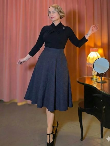 Model trägt einen klassischen Vintage Tellerrock in Schwarz mit Seitentaschen und hoher Taille, kombiniert mit einem eleganten Oberteil im 50er-Jahre-Stil.