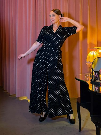 Schwarzer Jumpsuit mit weißen Punkten, Wickeloberteil und weitem Bein an einem Modell.