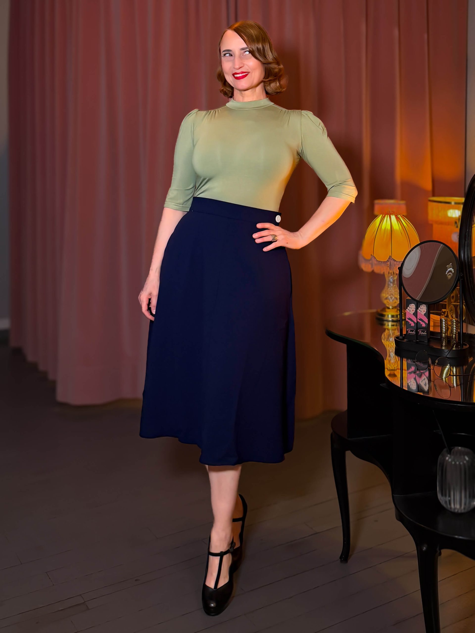 Frau präsentiert den dunkelblauen Classic 1940s A-Line Skirt mit lindgrünem Jersey Top.